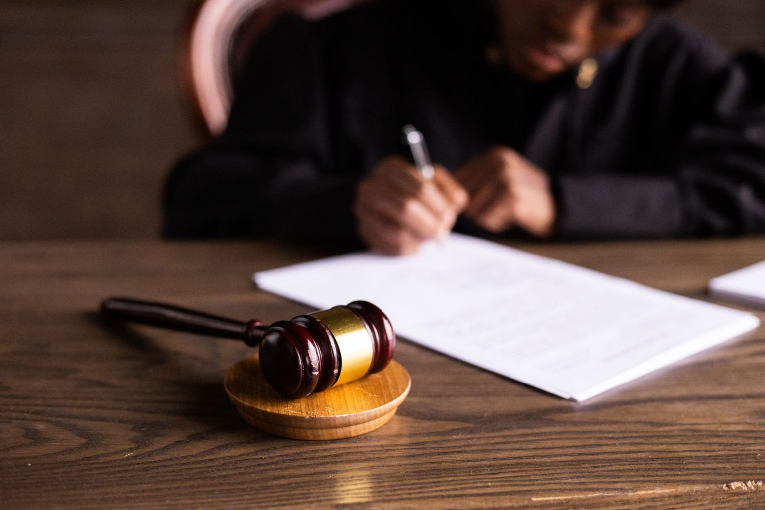 contesting-a-will-in-california-and-what-happens-if-you-lose A judge's gavel on a wooden desk while a judge signs court papers in the background