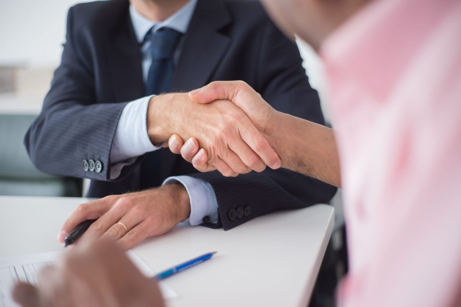 how-businesses-can-reduce-the-risk-of-commercial-disputes Two people shaking hands across an office desk after agreeing a contract