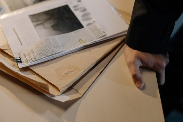 Case files and newspaper clippings on a desk during a criminal investigation