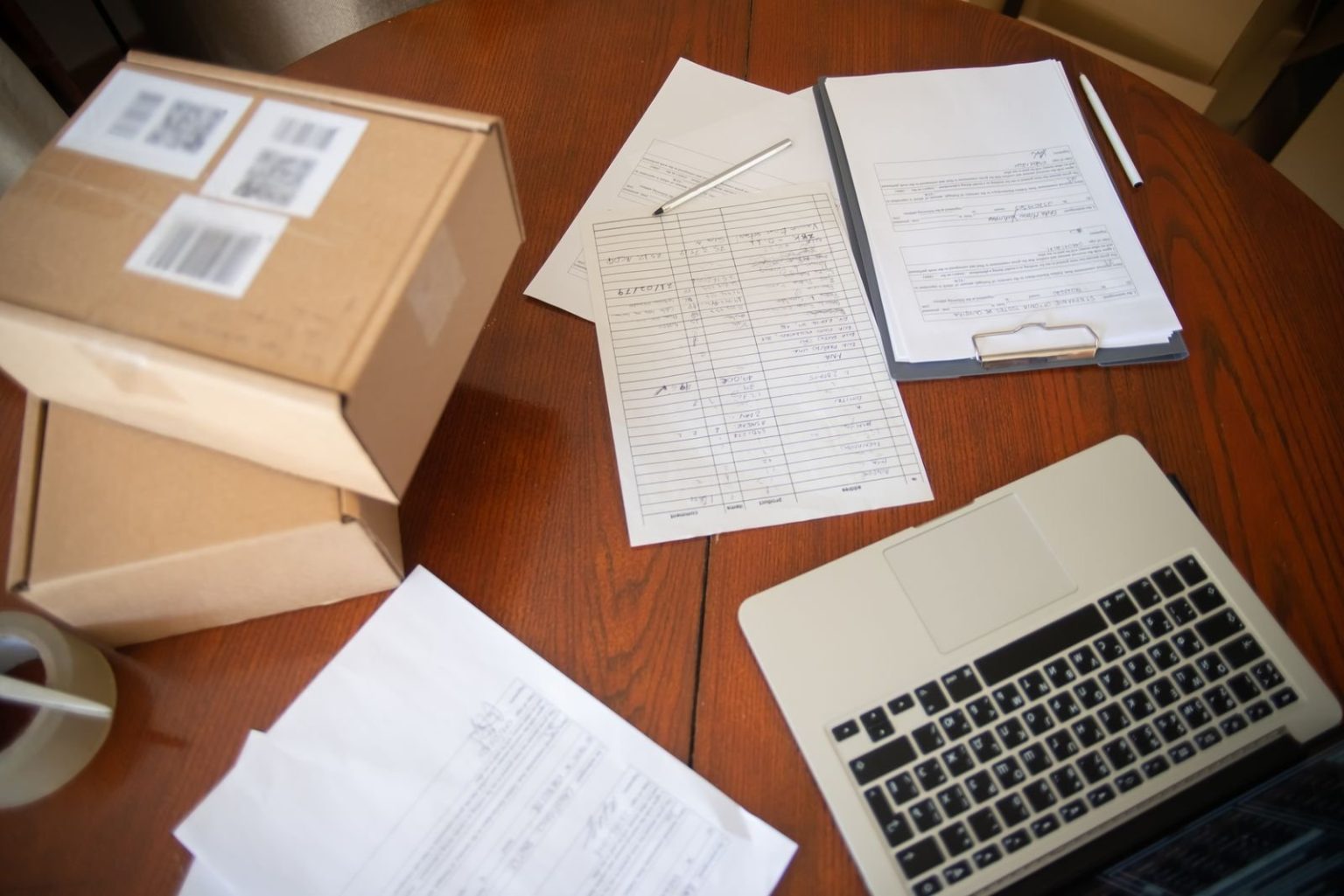 Parcels, shipping paperwork and a laptop on a desk for an online business