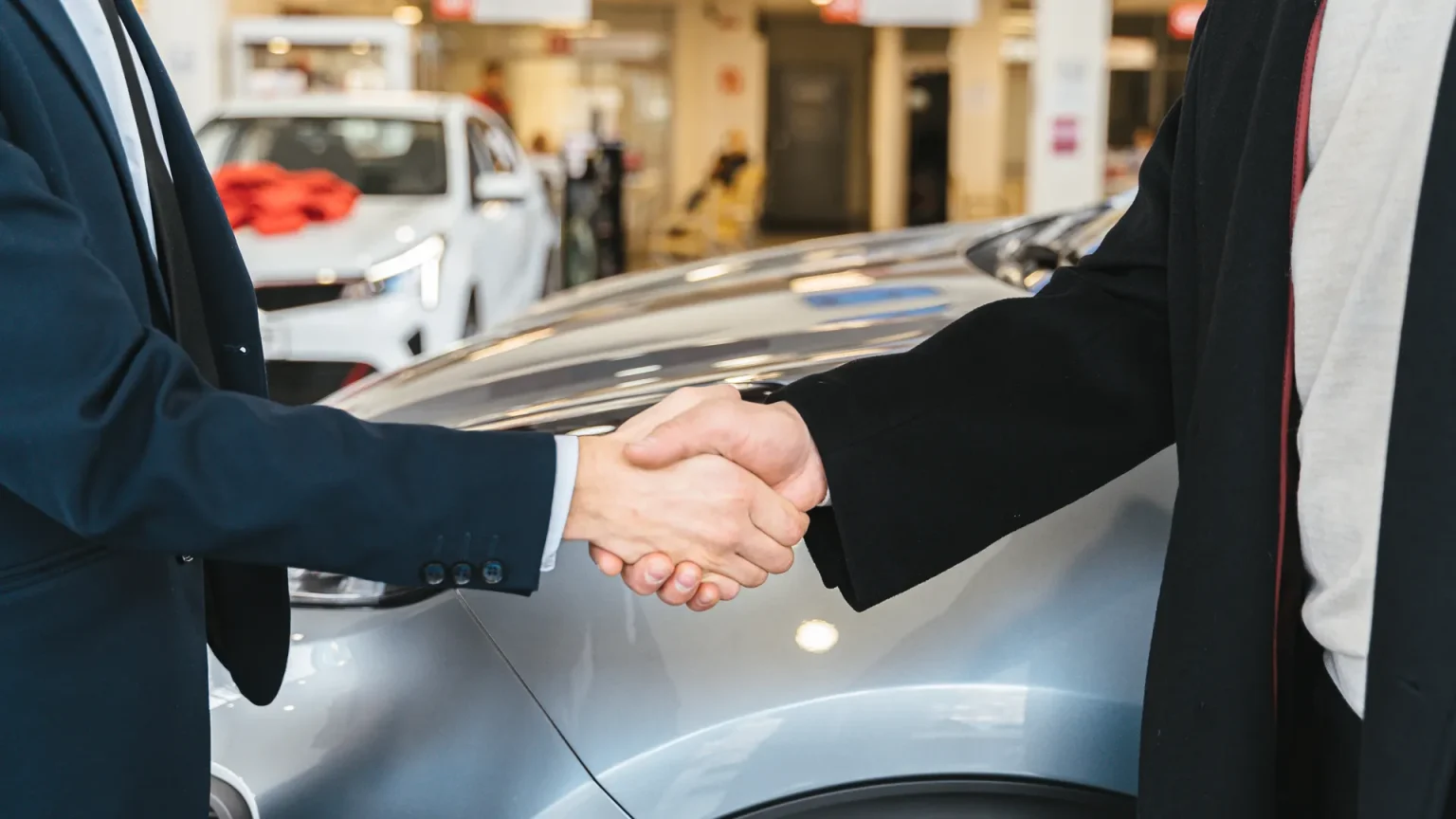 Car dealer and customer shaking hands on a finance deal in a showroom