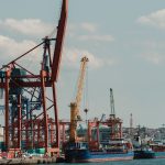 Cargo ships and cranes at a seaport under a clear sky