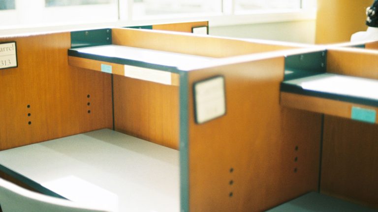 Empty wooden desks in a sunlit open-plan office