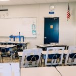 Empty classroom with desks, a whiteboard and an American flag
