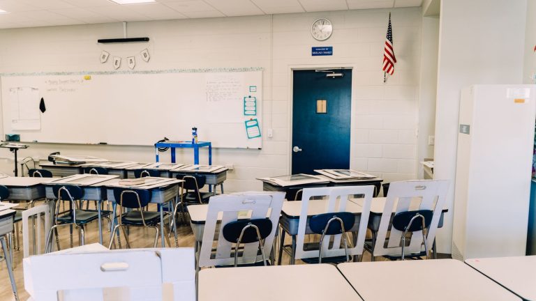 Empty classroom with desks, a whiteboard and an American flag