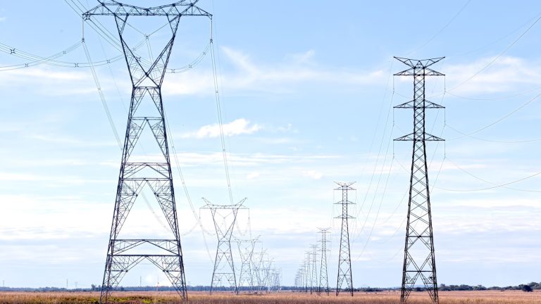 High voltage electricity pylons across an open field High voltage electricity pylons across an open field