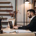 Lawyer working on a laptop beside a Lady Justice statue
