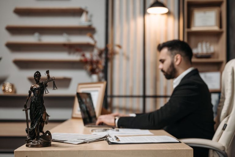 Lawyer working on a laptop beside a Lady Justice statue