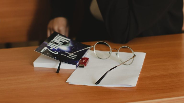 Eyeglasses and a book on a wooden desk
